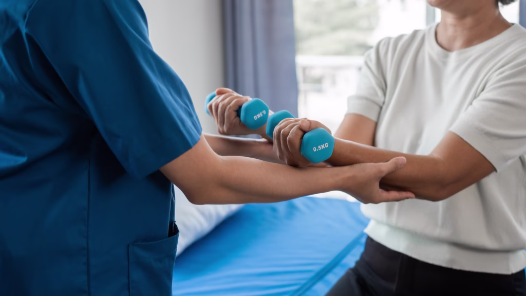 Physiotherapist guiding a patient through light hand-weight exercises
